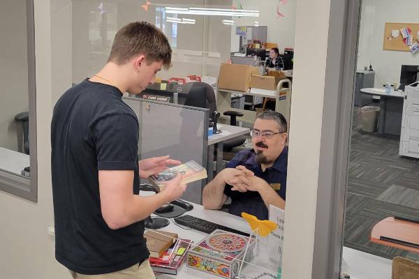 a staff member helping a student checkout a book